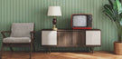 retro modern living room with green wall, sideboard and accent chair, lamp and vintage TV