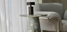 round green marble side table beside grey accent chair with black statement lamp