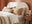 how to pick a bed buying guide banner - cosy bedroom with cream boucle fabric bed with soft orange and cream bedding, wooden bedside table, terracotta wall