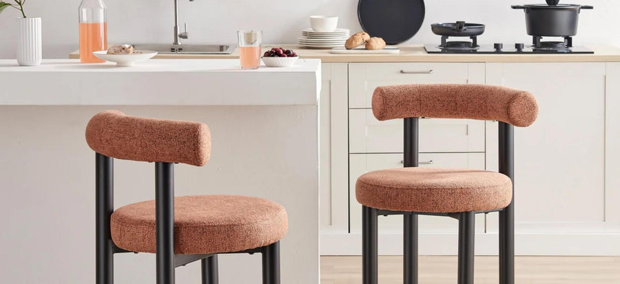 tips for choosing the perfect bar stool - image features 2 modern styling bar chairs with teracotta orange fabric, barrel style round back cushion, round seta, and black round legs in modern kitchen
