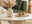 is a coffee table essential for living room design - features round cream marble pedestal coffee table in warm cosy living room with green sofa