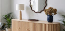 oak wood sideboard with ribbed fluted paneling, and walnut wood wiggly framed wall mirror for mixed wood styling guide