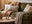 settee vs sofa vs couch - what's the difference? Green cosy sofa with throws and cushions, round cofee table and green glass table lamp
