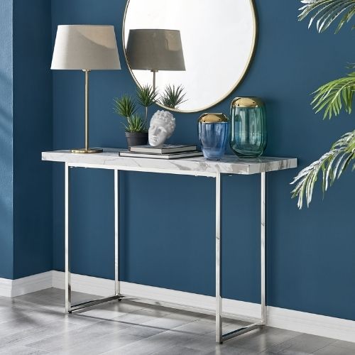 console table with white marble effect top and silver legs, with ancient greece inspired accessories and large round mirror behind.
