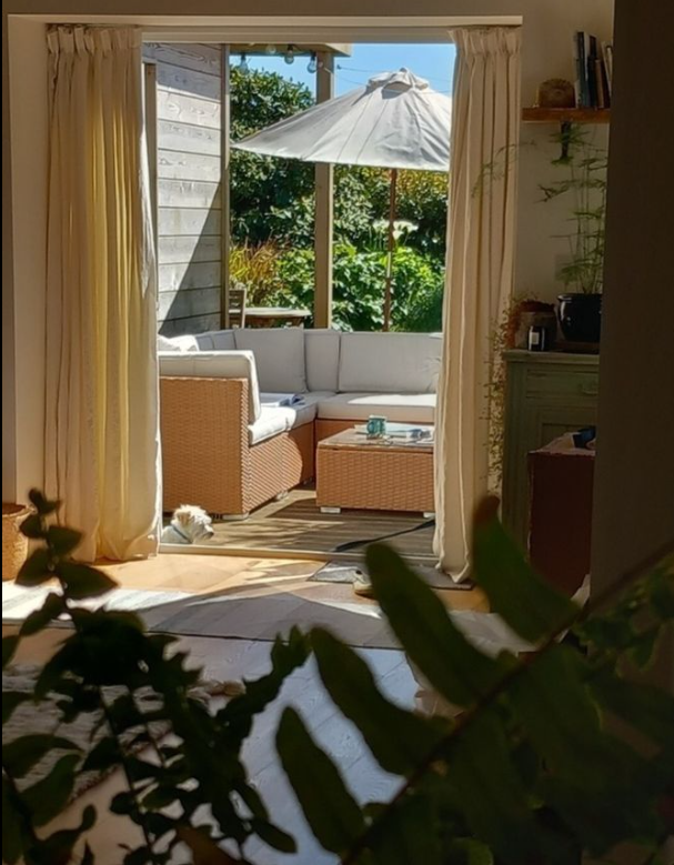 mediterranean bedroom inspiration showing open plan living space of warm wood and rustic sideboard with open balcony door and rattan garden furniture set beyond