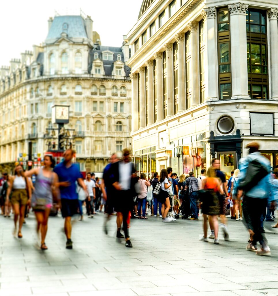 Busy town centre in the UK with blurred people walking and tall Victorian ornate buildings beyond