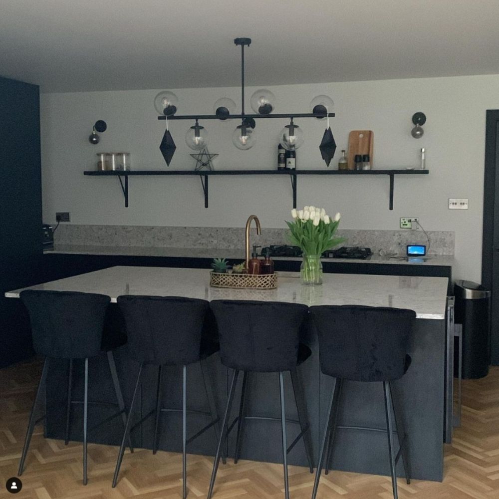 modern black and white kitchen featuring kitchen islans and 4 black velvet bar stool chairs with tapered black legd