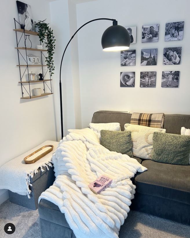 modern cosy living room with grey sofa and black metal arc lamp; pillows and throws on sofa