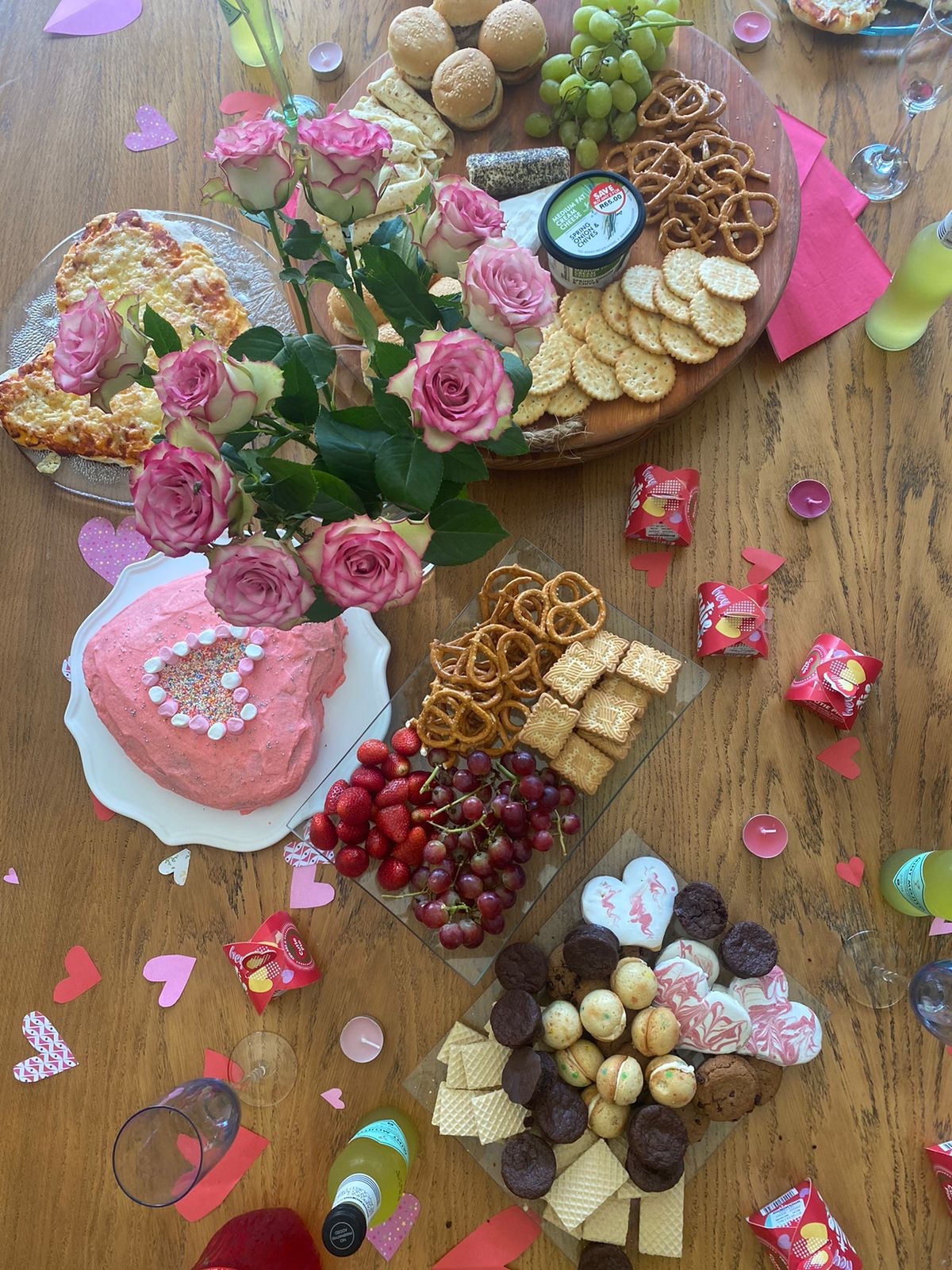 wooden dining table with Valentines heart cake, strawberries and pretzels 