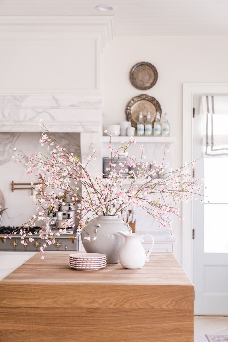 modern white kitchen with wooden kitchen islans, vase of pink blossoms